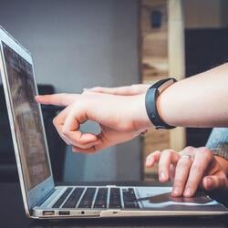 person pointing at a laptop screen