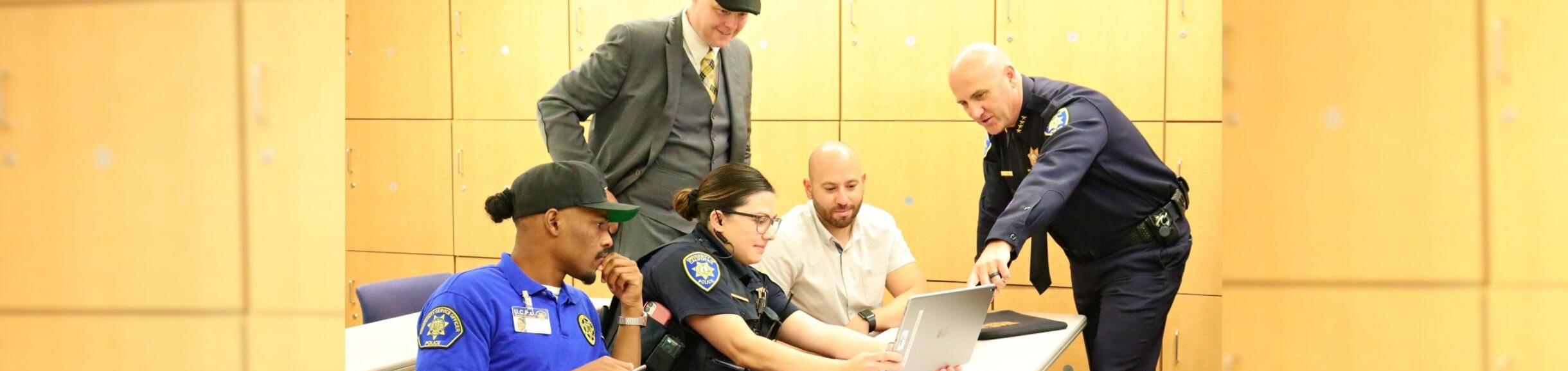 Chief Information Security Officer looks at laptop with UCPD team at station