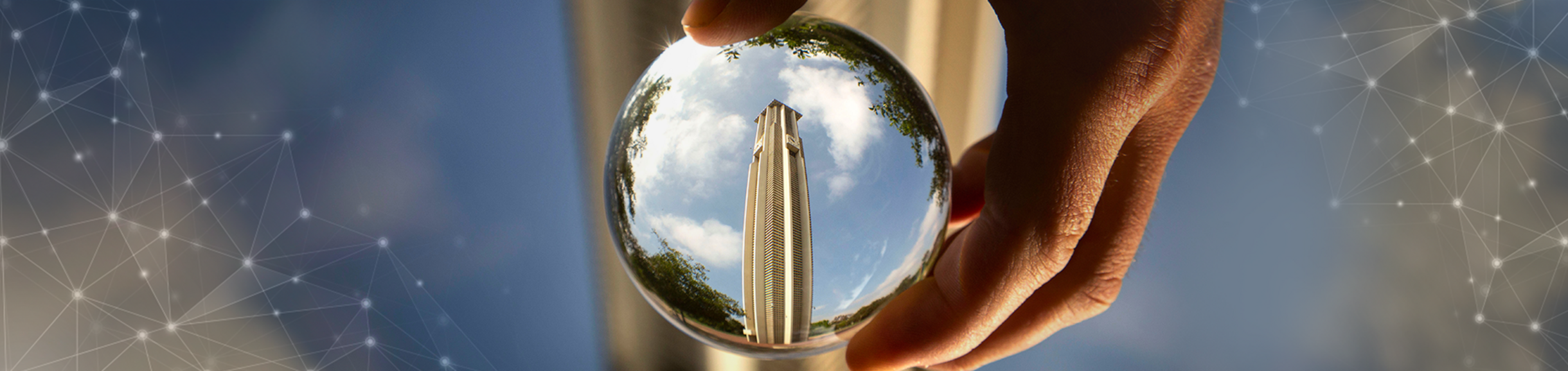 A hand holding a lens showing the UCR Bell Tower 