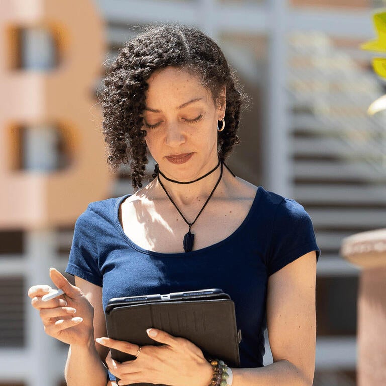 Woman in a blue shirt stands with tablet  in her hands