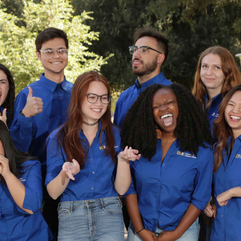 Group of cheerful and energetic graduate fellows wear matching shirts and pose