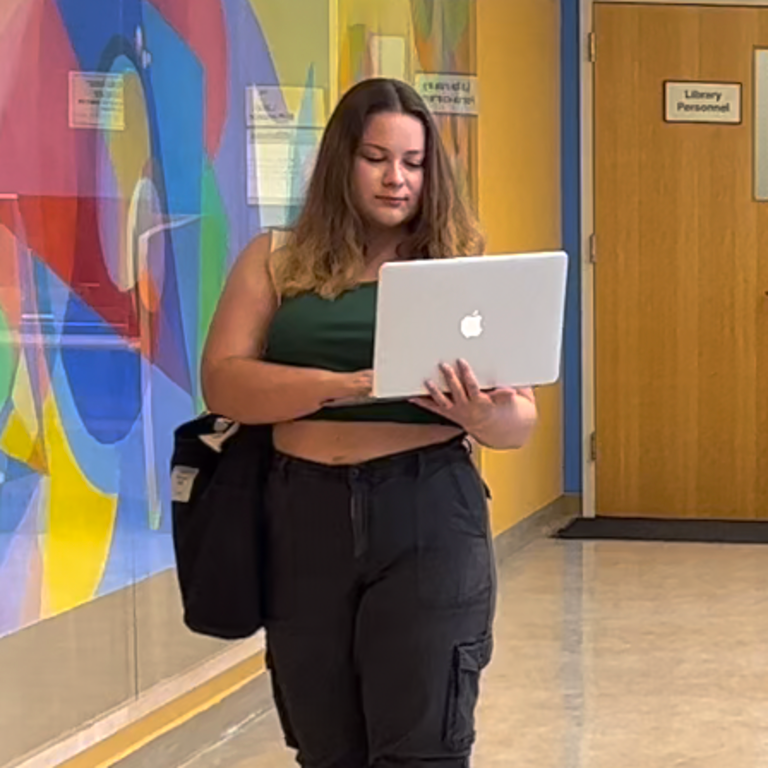 Blond student in green shirt uses a laptop at the library