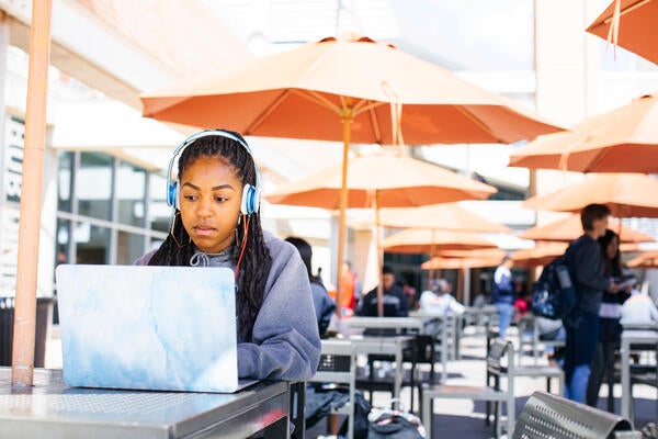 A student wearing headphones and on their laptop while sitting at the HUB
