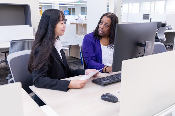 Female staff member assisting a student on a device