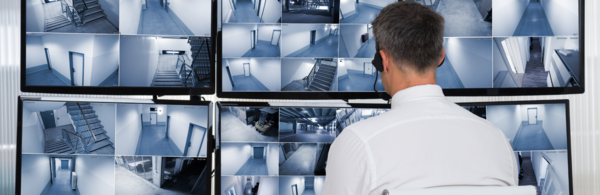 man in front of monitor watching many screens