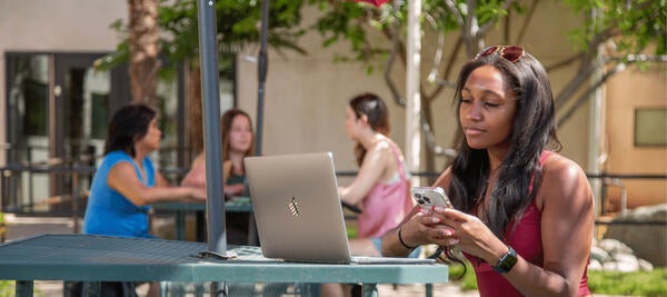 Woman sits with laptop and phone