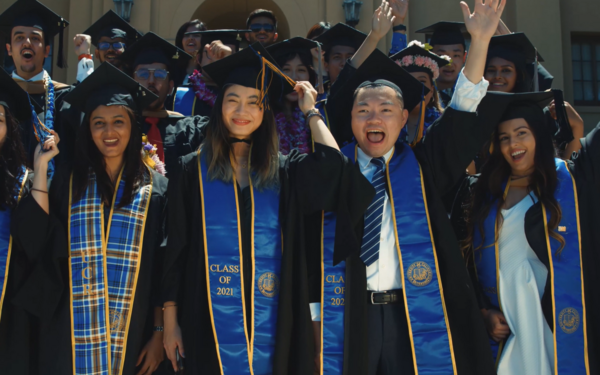 A group of students wearing graduation regalia celebrating.