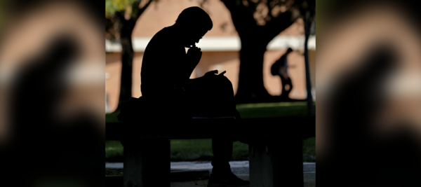 Silhouette of a student looking down at book