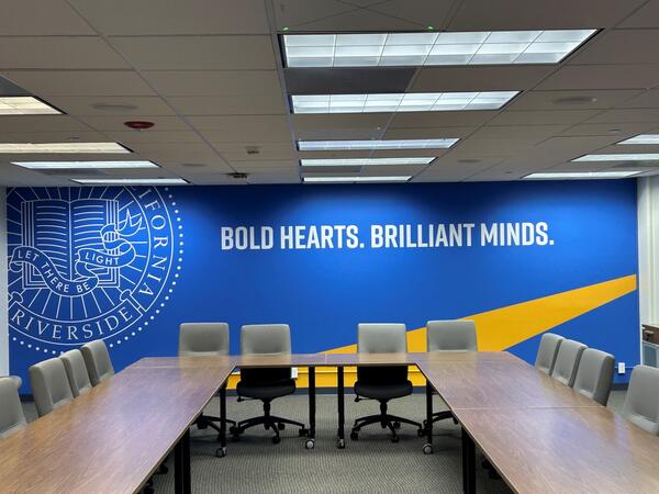 conference room with tables and chairs and UCR logo in the background