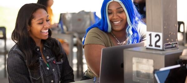 two laughing students look at computer