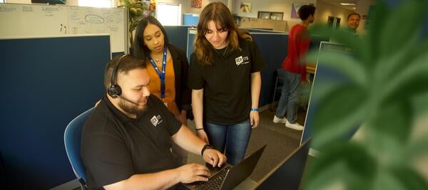 team of ITS workers in black shirts look at computer