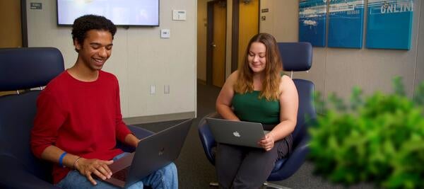 smiling students work separately on laptops