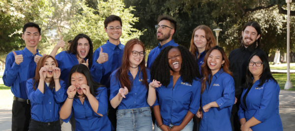 Group of cheerful and energetic graduate fellows wear matching shirts and pose