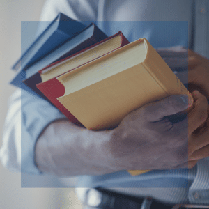 man holding a stack of 8 colorful books