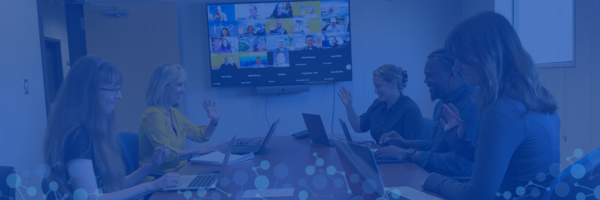 staff members in conference room wave at others in online Zoom room