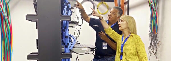 Two ITS staff technicians point at networking wires in cloud storage room