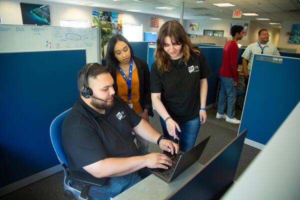 ITS staff members in black shirts looking at computer