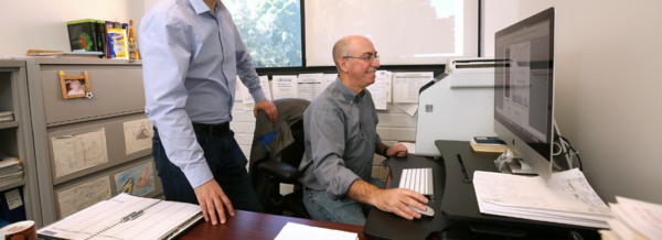 Two staff members looking at a computer monitor in an office