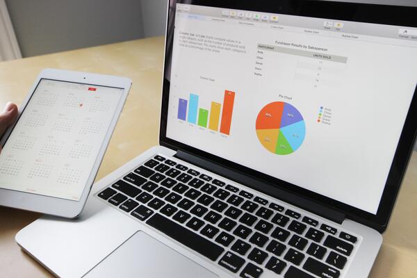 person holding tablet and laptop with business charts