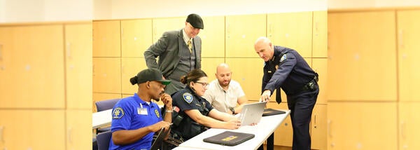 Chief Information Security Officer looks at laptop with UCPD team at station