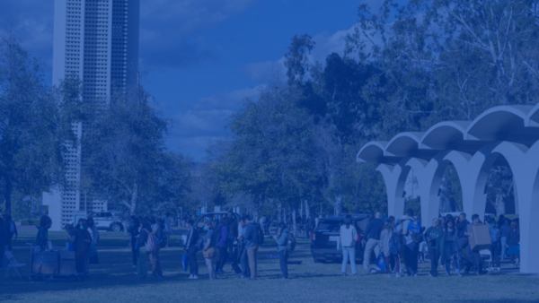 Students walking by Rivera Library arches with the Bell Tower in the distance