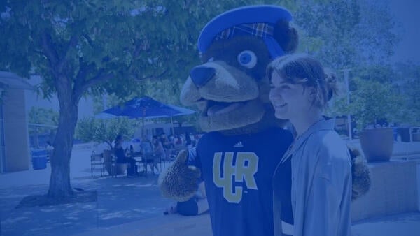 A student poses with Scotty Bear mascot at the HUB