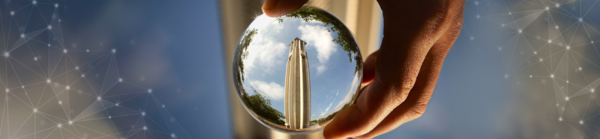 A hand holding a lens showing the UCR Bell Tower 