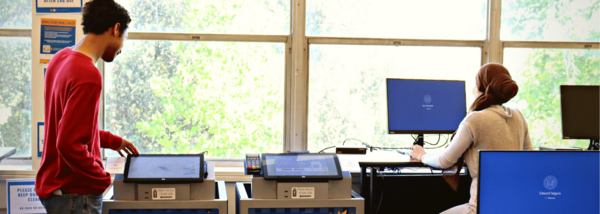 student looks at printer and other on desktop computer