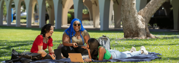 laughing-student-group-sit-on-lawn-using-mobile-computers