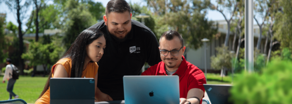 staff members overlook two laptops outdoors