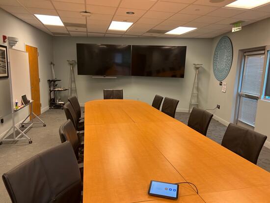 empty conference room with long table, chairs, and TVs
